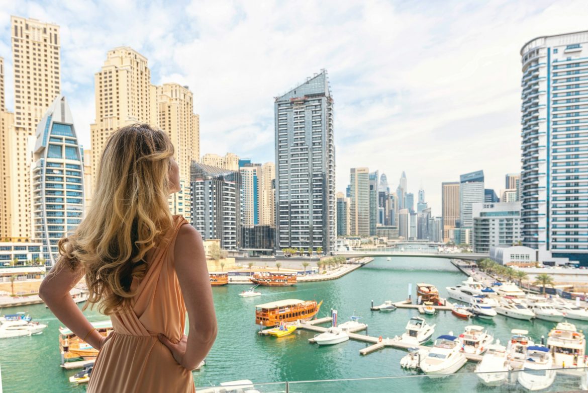 Woman in Dubai Marina, United Arab Emirates. Attractive lady wearing a long dress admiring Marina